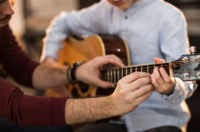En gitarist får instruksjoner på hvordan han skal spille.